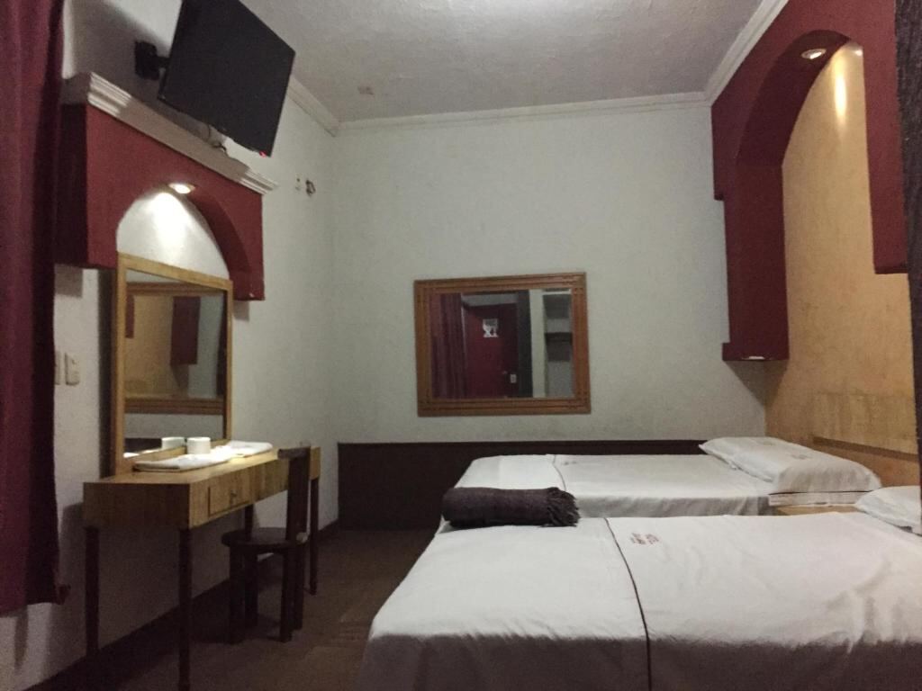 Twin beds and desk in a room at Hotel Xalapa